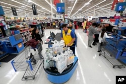 FILE- Walmart associate Luis Gutierrez, center, checks out a customer at a Walmart Supercenter in Houston, Texas, Nov. 9, 2018.