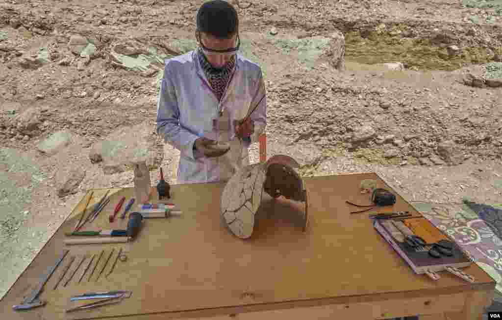 Egyptian archeologist Mohamed Said piecing together pottery found inside the workmen huts in the Luxor's Valley of Monkeys in Egypt. (H. Elrasam/VOA)