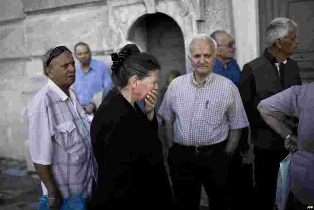 Pensioners wait outside a branch of the National Bank of Greece to get their pensions on June 29, 2015 in Athens.