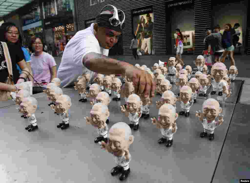 Christopher "Tree Wizard" Pereira, pembuat boneka miniatur yang menyebut dirinya artis politis, memamerkan koleksi boneka mantan perdana menteri Singapura Lee Kuan Yew di pinggir jalan Singapura, 20 April 2013.