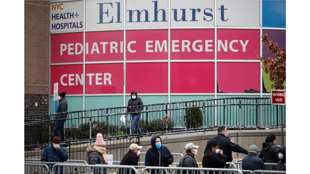 FILE - In this March 25, 2020, file photo, a woman exits a new coronavirus testing site while others wait in line at Elmhurst Hospital Center, in the Queens borough of New York.
