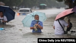 河南省鄭州市的居民趟過齊腰洪水的街道。 （2021年7月20日）