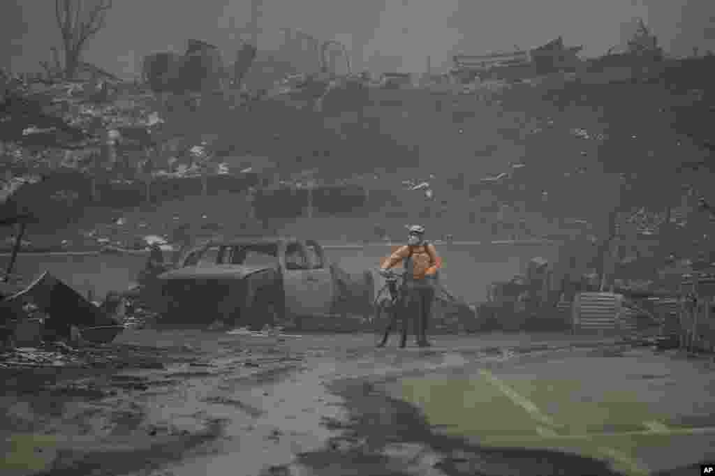 A man walks his bike among the ruins left behind by the Palisades Fire in the Pacific Palisades neighborhood of Los Angeles, California. Multiple massive wildfires are tearing across the Los Angeles area with devastating force. The flames drove residents to make desperate escapes from burning homes through ferocious winds and towering clouds of smoke. At least two people have died and numerous have been injured.
