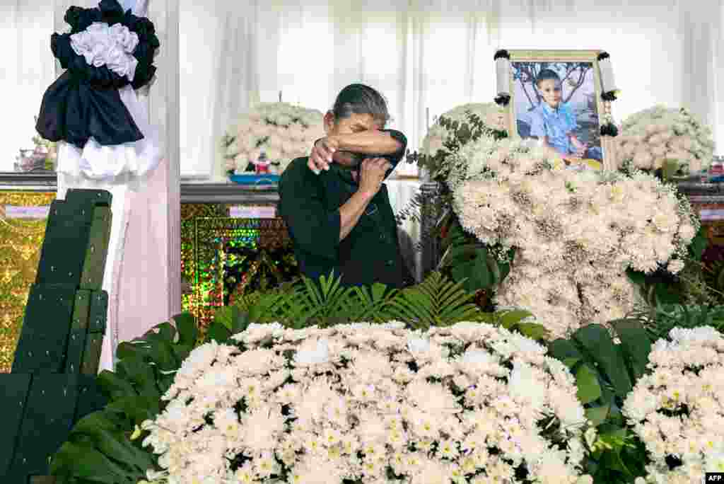A relative cries in front of the portrait and coffin of a victim of a school bus fire at Wat Khao Phraya Sangkharam School in Uthai Thani, Thailand. Grieving families offered prayers for 23 children and their teachers killed in a horrifying school bus fire as the government vowed a crackdown on unsafe vehicles. 