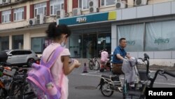 一个女孩站在北京街头一个新东方校外补习学校的附近。（2021年7月26日）