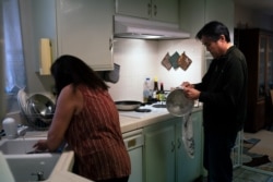Kerry Osaki, right, helps his wife, Lena Adame, in the kitchen in their Fountain Valley, California, home, November 25, 2020. This year, their traditions have fallen to the pandemic that took the life of Osaki's 93-year-old mother.