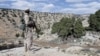 FILE - A Lebanon Hezbollah fighter carries his weapon as he stands in Khashaat, in the Qalamoun region after they advanced in the area, May 15, 2015. 