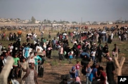 FILE - In this June 14, 2015, photo taken from the Turkish side of the border between Turkey and Syria, in Akcakale, Sanliurfa province, southeastern Turkey, thousands of Syrian refugees walk in order to cross into Turkey.