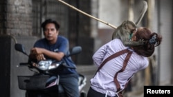 A long-tailed macaque attacks an employee of a shop before officials started capturing monkeys in Lopburi, Thailand, Feb. 3, 2024.