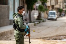 A member of the Kurdish Internal Security Forces of Asayesh stands guard on a deserted street in Syria's northeastern city of Hasakah, April 30, 2020, following measures taken by Kurdish-led local authorities there to limit the spread of COVID-19.
