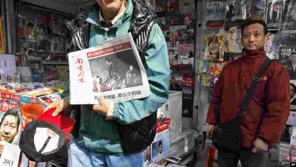 2013年1月10日,一位男士在广州《南方周末》总部附近的一处报刊亭展示最新版的《南周》。