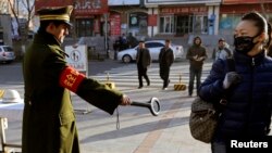 지난달 17일 중국 신장 위구르 자치구 우루무치에서 한 보안요원이 행인들의 가방에 금속탐지기 검사를 하고 있다. (자료사진)