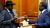FILE - South Sudan's President Salva Kiir (L) and the country's rebel leader, Riek Machar, exchange signed peace agreement documents in Addis Ababa May 9, 2014.
