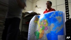 Seorang pekerja percetakan di Changsa, provinsi Hunan, memegang peta China baru yang telah disetujui, yang mencakup pulau-pulau sengketa di Laut China Selatan. (Foto: Dok)