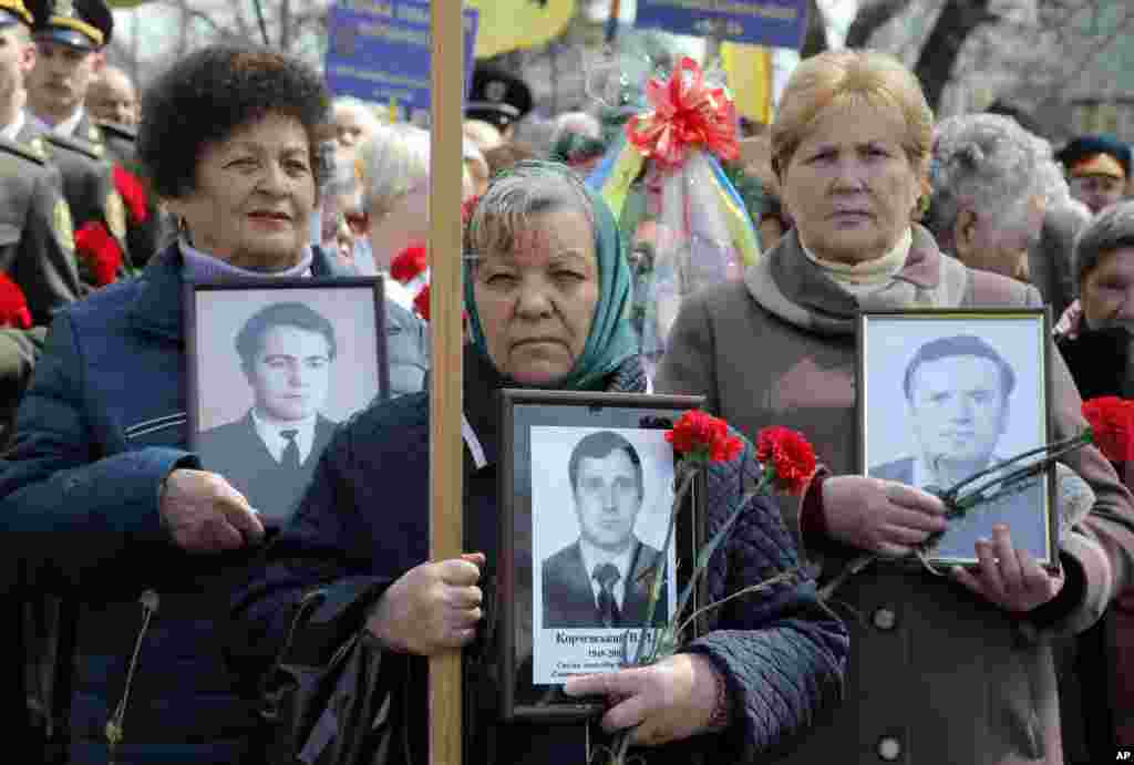 Widows of Chernobyl victims hold portraits of their husbands who died following the clean-up operations for the 1986 Chernobyl nuclear explosion, at Chernobyl's victim monument in Ukraine's capital Kyiv, April 26, 2017.