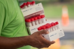 FILE PHOTO: Healthcare worker carries specimen collection tubes at COVID-19 drive-in testing location in Houston, Texas.