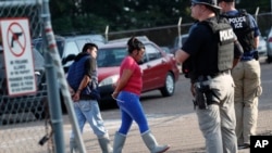 Dua migran ditangkap di sebuah pabrik pengolahan makanan Koch Foods Inc. di Morton, Mississippi, Rabu, 7 Agustus 2019.
