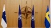 Bendera Finlandia (kiri) dan bendera Swedia (kanan) mengapit bendera NATO terpajang sebelum upacara penerimaan permohonan keanggotaan dari Finlandia dan Swedia, 18 Mei 2022. (Foto: Johanna Geron/Pool via AP)