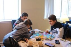 Syrian refugee Mohamed Almadani, 14, plays a game with younger sister Esraa, 10. He remembers gunfire and glass shattering in his home when the conflict in Syria escalated. (K. Khan/VOA)