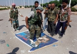 FILE - A Free Syrian Army fighter, center, steps on a poster depicting Syrian President Bashar al-Assad, at Tal Abyad, a Turkish-Syrian border crossing captured by the rebels, in eastern Syria, Sept. 22, 2012.