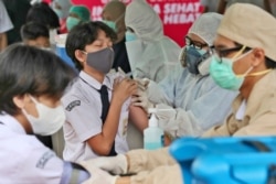 Seorang siswa bereaksi ketika seorang pekerja medis menyuntikkan vaksin Sinovac untuk anak-anak antara 12-17 tahun di sebuah sekolah di Tangerang. (Foto: AP)
