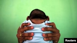 FILE - Jackeline, 26, holds her son who is 4-months old and born with microcephaly, in front of their house in Olinda, near Recife, Brazil, February 11, 2016.