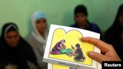 Seorang konselor memegang kartu yang digunakan untuk mengajari perempuan tentang bahaya sunat perempuan.