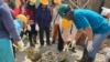 Seorang pelatih (baju biru), memandu dua orang ibu mempraktekkan cara membuat adukan semen untuk pengecoran tiang bangunan rumah, 7 Desember 2019. (Foto: VOA/Yoanes Litha)
