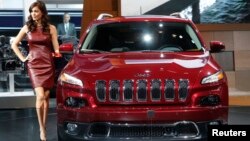 A model poses next to a Jeep Cherokee during the press preview day of the North American International Auto Show in Detroit, Michigan January 14, 2014. 
