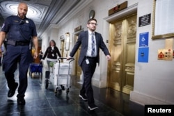 Polisi Capitol AS mengawal anggota staf Komite Penyelidik saat mereka mengangkut kotak dokumen setelah rapat komite untuk membahas pengembalian pajak mantan Presiden Donald Trump di Capitol Hill di Washington, AS, 20 Desember 2022. (REUTERS/Evelyn Hockstein)