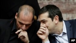 Greece's Prime Minister Alexis Tsipras chats with Greece's Finance Minister Yanis Varoufakis during a presidential vote in Athens, Feb. 18, 2015.