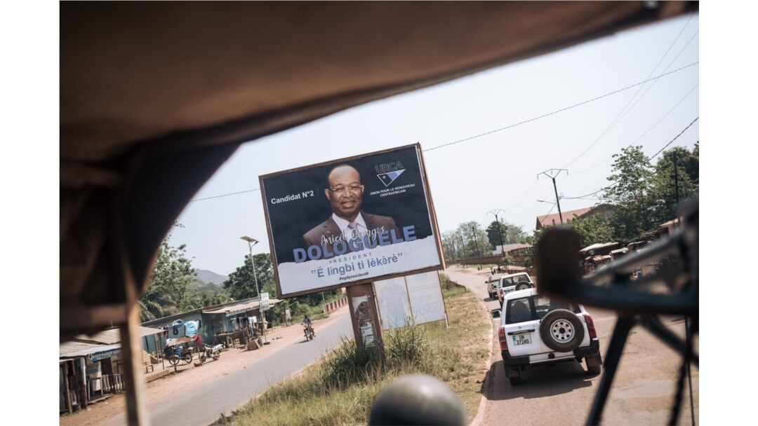 A convoy of the U.N. Multidimensional Integrated Stabilization Mission in the Central African Republic passes by an election poster of opposition candidate Anicet Georges Dologuélé, in Bangui, Dec. 25, 2020.