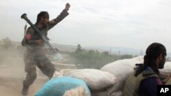 FILE - An Afghan National Army soldier (L) shouts at Taliban fighters, after firing a rocket towards Taliban positions, on the outskirts of Kunduz, northern Afghanistan, April 16, 2016.