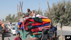 Afghan families leave their houses after fighting between the Afghan military and Taliban insurgents in Helmand province, southern of Afghanistan, Oct. 13, 2020. 