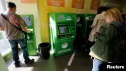 Sejumlah nasabah sedang menggunakan anjungan tunai mandiri (ATM) di dalam kantor Sberbank – bank terbesar di Rusia -- di St. Petersburg, 16 September 2014. AS mempertimbangkan untuk mendepak Rusia dari sistem pembayaran antar bank atau SWIFT sebagai sanksi atas invasi ke Ukraina
