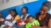 In this photo taken on Monday, Nov. 3, 2014, mothers wait inline for their children to be vaccinated by heath workers at the Pipeline Community Health Center, situated on the outskirts of Monrovia, Liberia. The Ebola outbreak has spawned a “silent killer,” experts say: hidden cases of malaria, pneumonia, typhoid and the like that are going untreated. (AP Photo/ Abbas Dulleh)