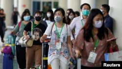 Para penumpang, sebagian besar wisatawan asing, dengan mengenakan masker tiba di terminal kedatangan bandara I Gusti Ngurah Rai, Denpasar, Bali (4/2). 
