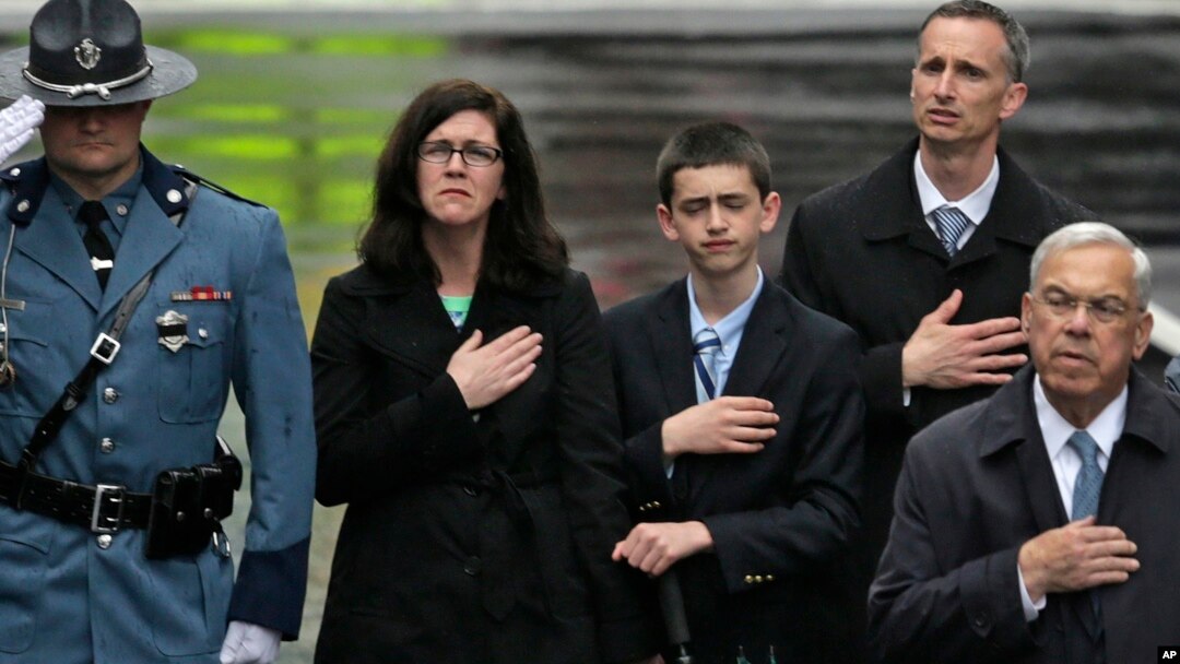 The family of Martin Richard, from left, mother Denise, brother Henry, and father Bill Richard, with former Boston Mayor Tom Menino, right, during a tribute in honor of the one year anniversary of the Boston Marathon bombings, Apr. 5, 2014, in Boston. 