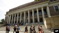 Orang-orang berjalan melewati pintu masuk Perpustakaan Widener, di belakang, di kampus Universitas Harvard, di Cambridge, 16 Juli 2019. (Foto: AP/Steven Senne)