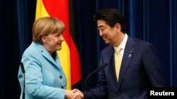德國總理默克爾(左)與日本首相安倍晉三(左)握手