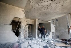 A Palestinian man gestures as he inspects a damaged building following an Israeli air strike, amid a flare-up of Israeli-Palestinian violence, in Gaza City, May 11, 2021.