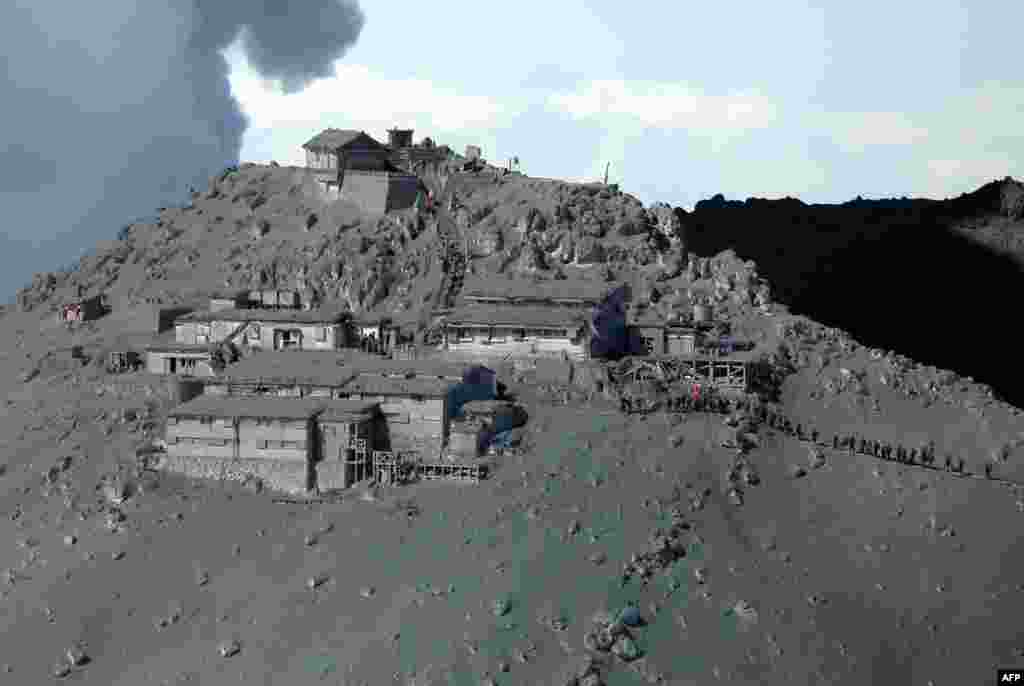 This aerial picture shows rescue workers and Self Defense Force soldiers searching for missing climbers and survivors among ash-covered mountain cottages and a Shinto shrine (above) on the top of Mount Ontake at Nagano prefecture, Sept. 28, 2014.