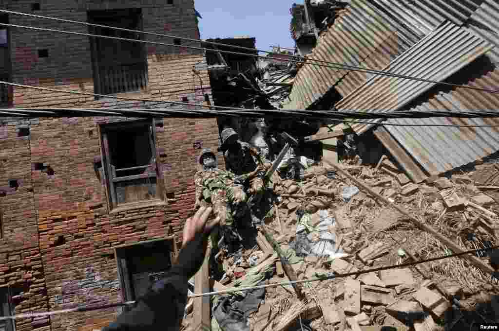 A Nepalese army soldier loses his balance while descending from a mound of rubble during the recovery of a body from a house, in the aftermath of Saturday's earthquake in Bhaktapur, Nepal.