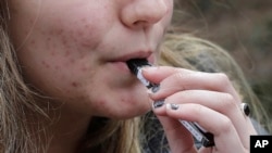 Seorang remaja SMA merokok vape dekat sekolah di Cambridge, Massachusetts, 11 April 2018. 