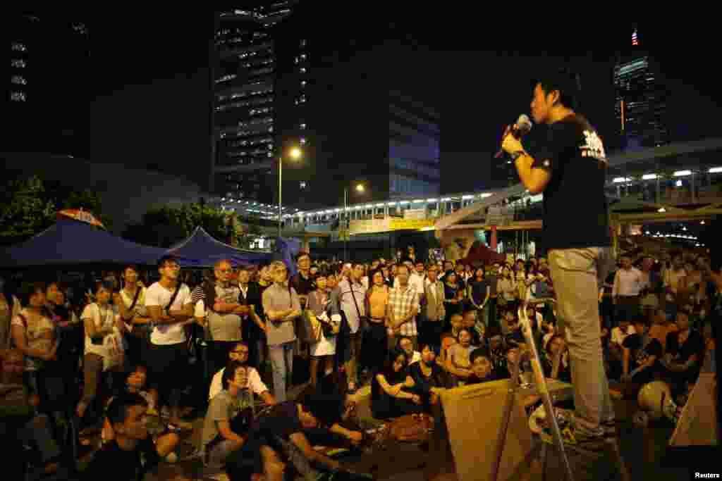 Pro-democracy demonstrators listen to a student's speech outside the government headquarters office in Hong Kong, Oct. 10, 2014.