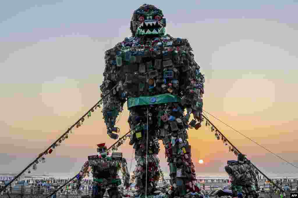 People walk past a giant sculpture of a &#39;Robot Monster&#39; made of plastic waste to raise awareness about the hazards of polluting the sea, at Cox&#39;s Bazar beach, Bangladesh.