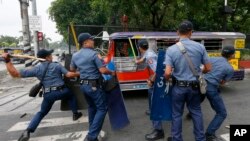 图片说明：菲律宾警方10月19日敲击一辆逃离在马尼拉美国大使馆外抗议的示威车辆。
