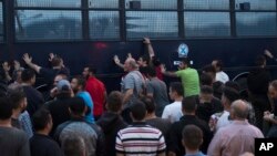 Para pengunjuk rasa menggoyang-goyangkan bus polisi di kota Mytilene di bagian timur pulau yang terletak di Laut Aegea, yaitu pulau Lesbos, 3 Mei 2018 (foto: AP Photo/Petros Giannakouris)