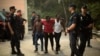 Police stand around a group of African migrants after they crossed the border fence from Morocco to Spain's North African enclave of Ceuta, Spain, Aug. 7, 2017.