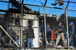 Migrants stand outside container houses in Moria refugee camp on the northeastern Aegean island of Lesbos, Greece, March 16, 2020.